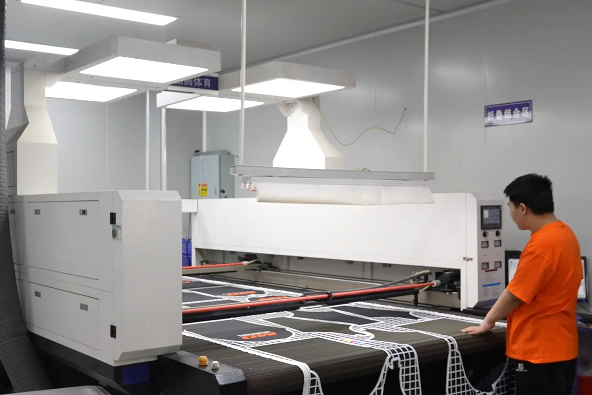 Operator monitoring printed jersey panels on a flatbed heat press