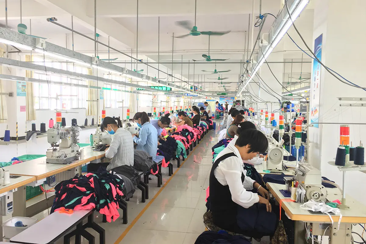 Workers sewing bright teamwear along a production line